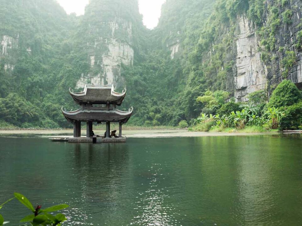 un temple vietnamien au milieu d'un lac entouré de falaises et de nature