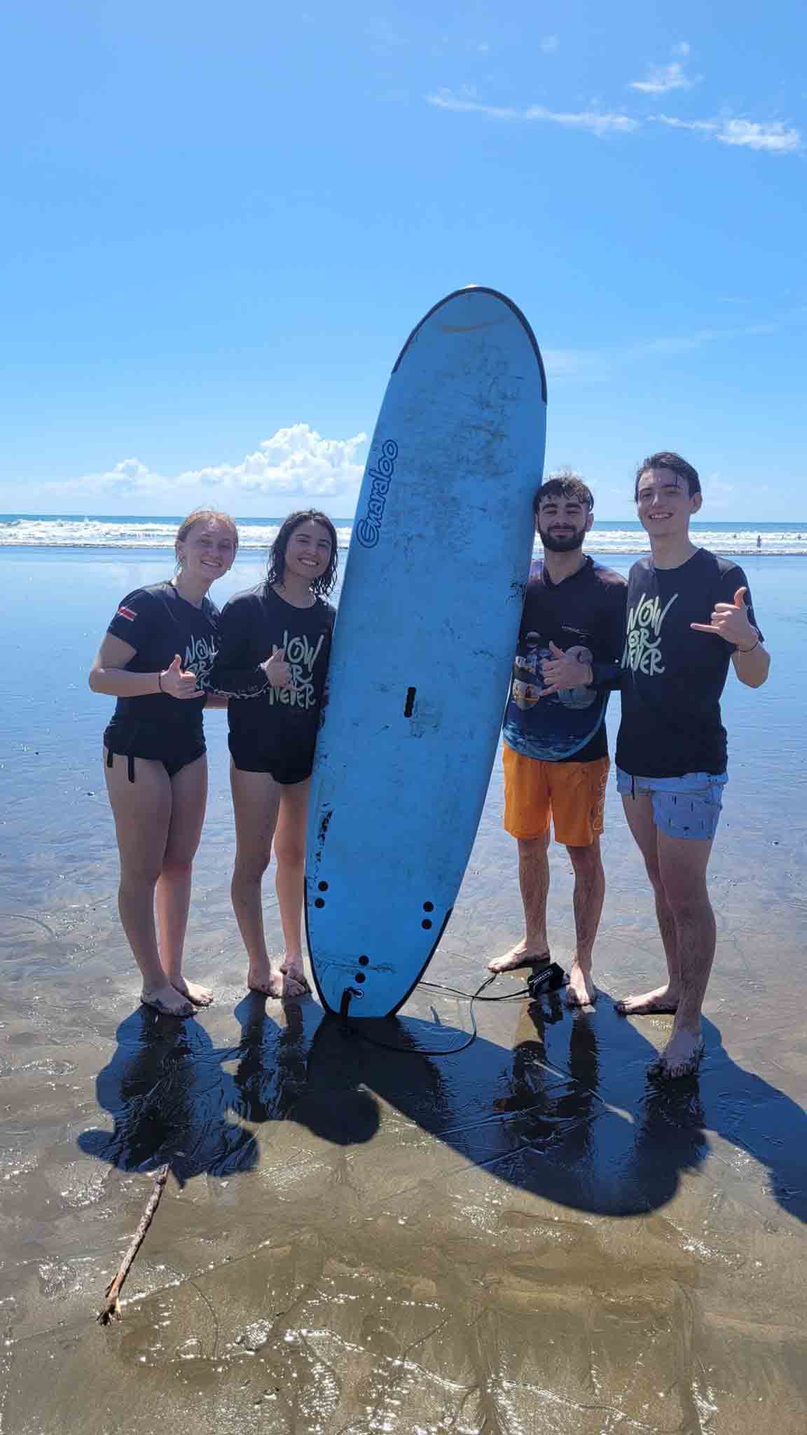 4 jeunes laurier-montois se tiennent autour d'une planche de surf au Costa-Rica