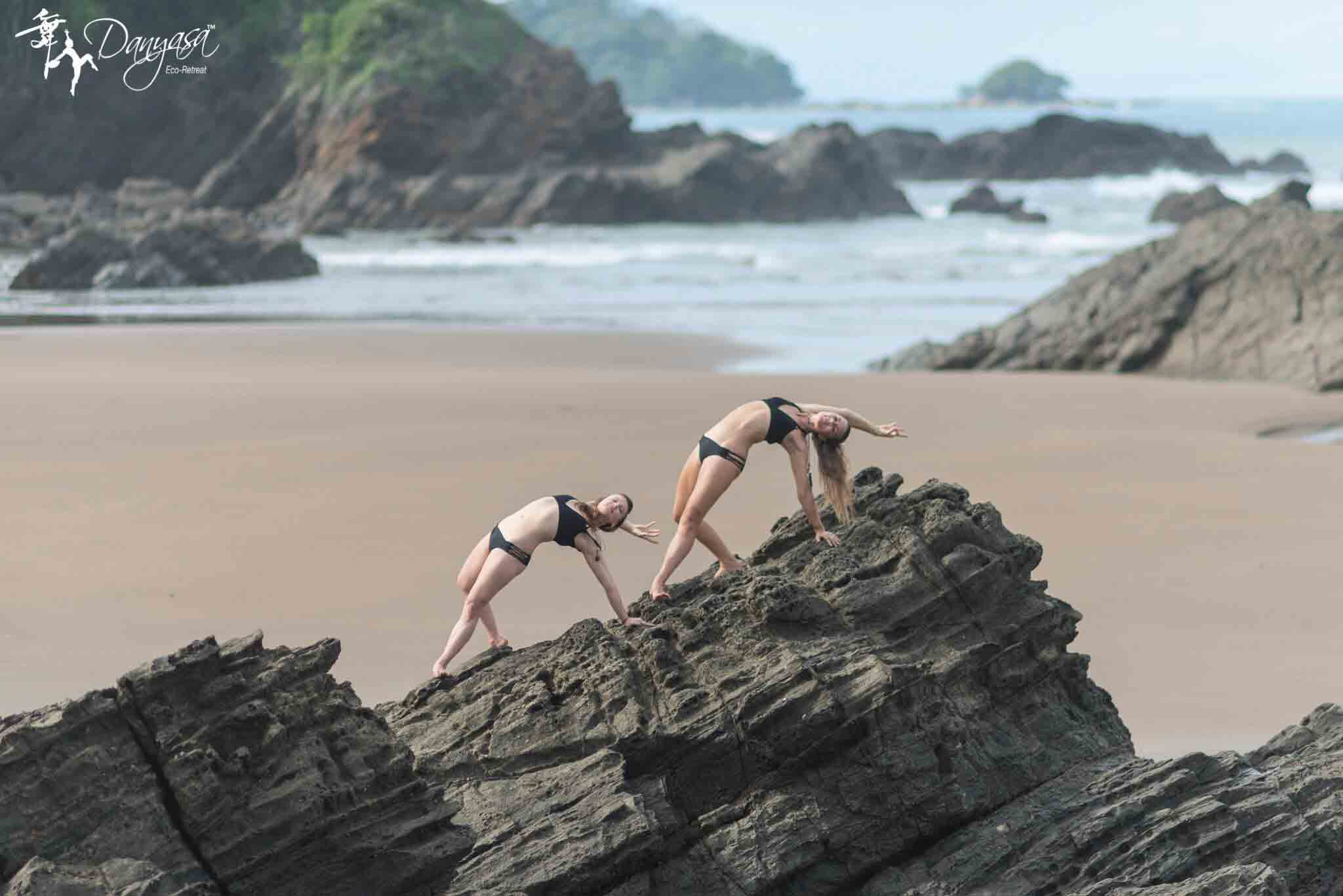 Deux femmes font du yoga sur un cap de roche situé sur la plage