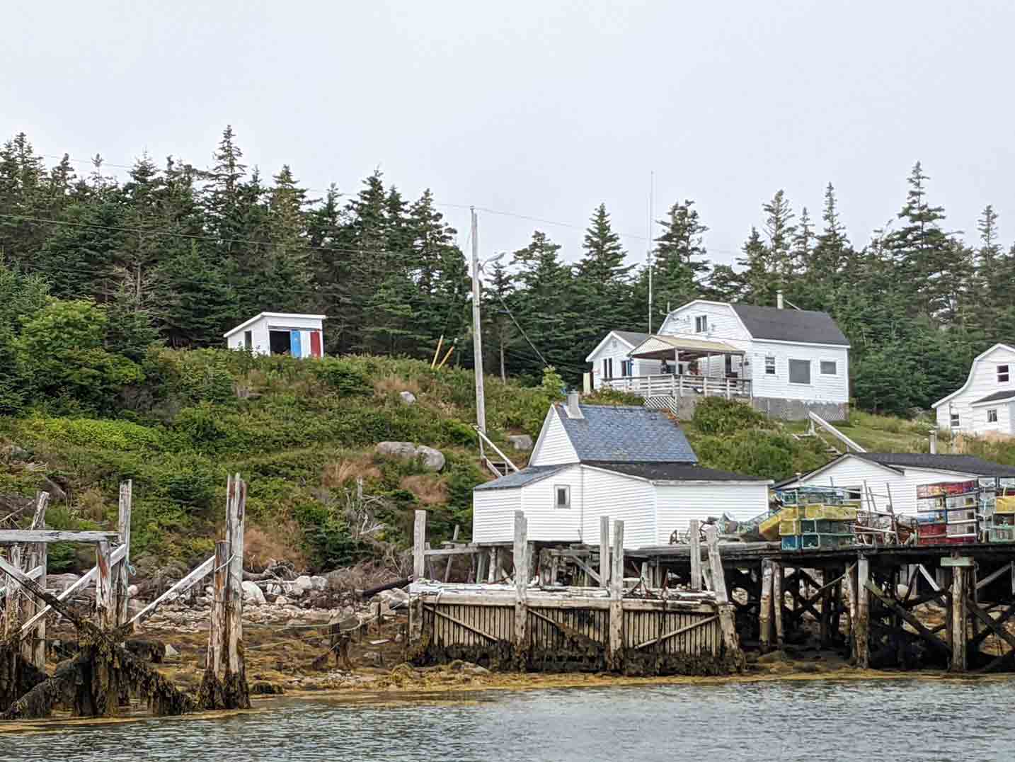 un village sur le bord de la mer avec une maison et un quai construit sur des pilotis