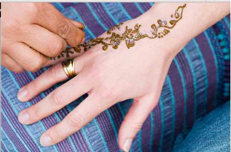 une femme blanche portant une bague se fait faire du henné par quelqu'un du Maroc