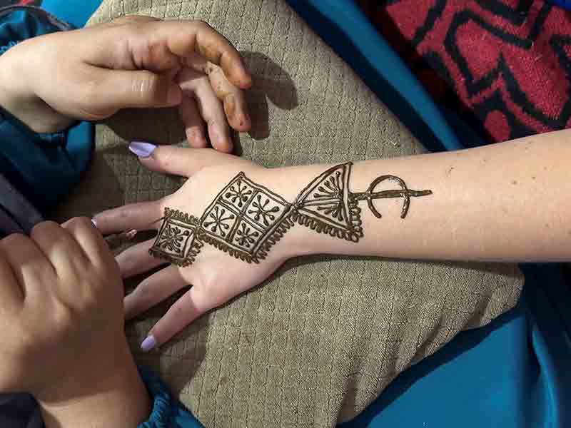 un femme blanche se fait faire un henné sur le bras